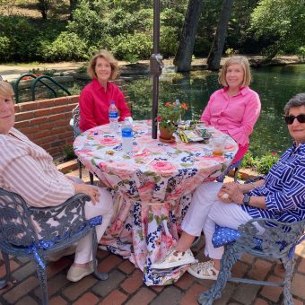 Four women sitting at a table outside on the patio.