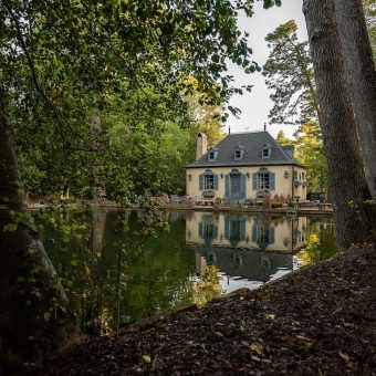 A house sitting on the water near some trees