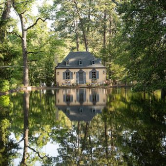 A house is reflected in the water of a pond.