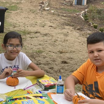 Two children sitting at a table with pumpkins.