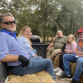 A group of people sitting on hay bales.