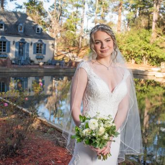 A bride holding her bouquet in front of the water.