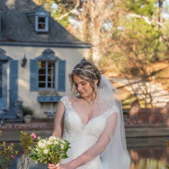 A bride holding her bouquet in front of the water.