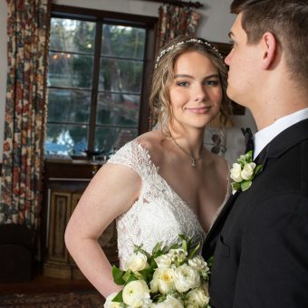A bride and groom looking at each other in front of a window.