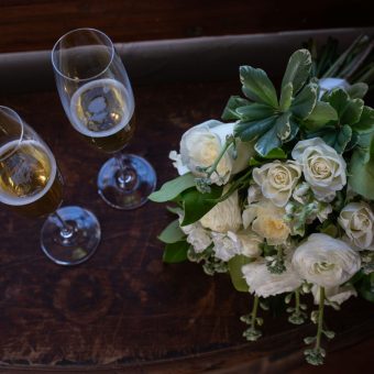 A bouquet of flowers and two glasses on a table.