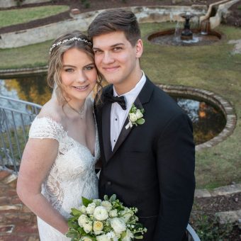 A young couple posing for a picture in front of a pond.