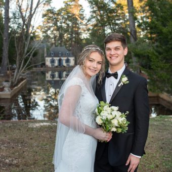 A young couple poses for a picture in front of a lake.