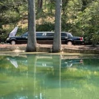 A black limo parked in the middle of a lake.